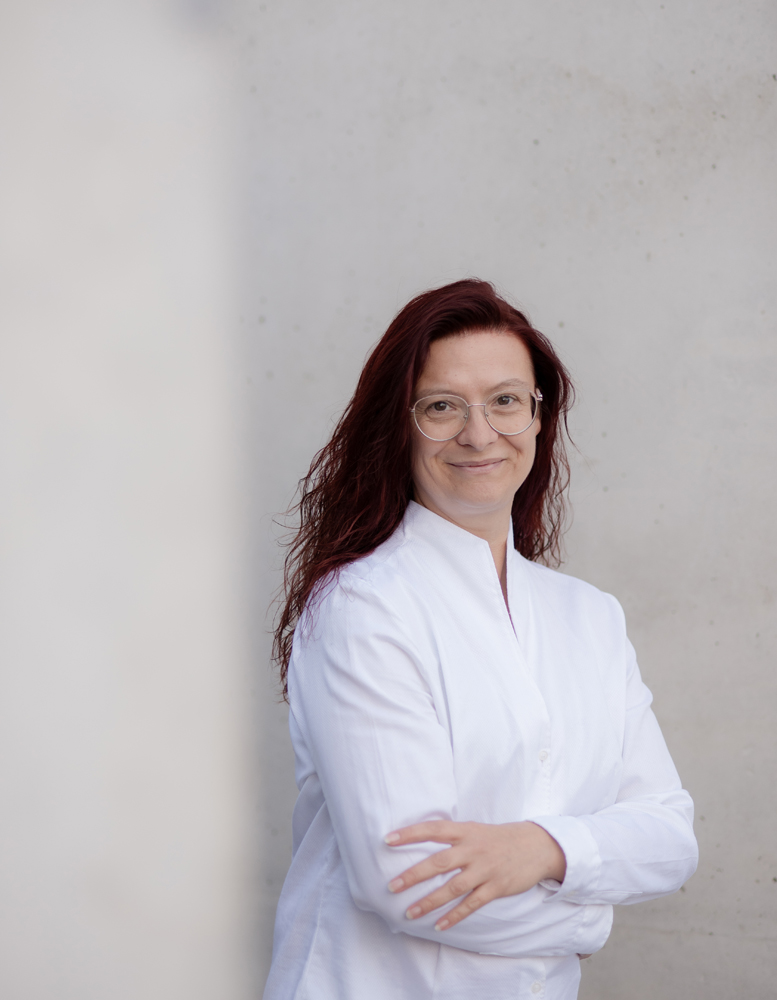 Tanja Wünsch steht an einer Mauer in weißen Klamotten und lächelt. Männergesundheit ist ihr Spezialgebiet.