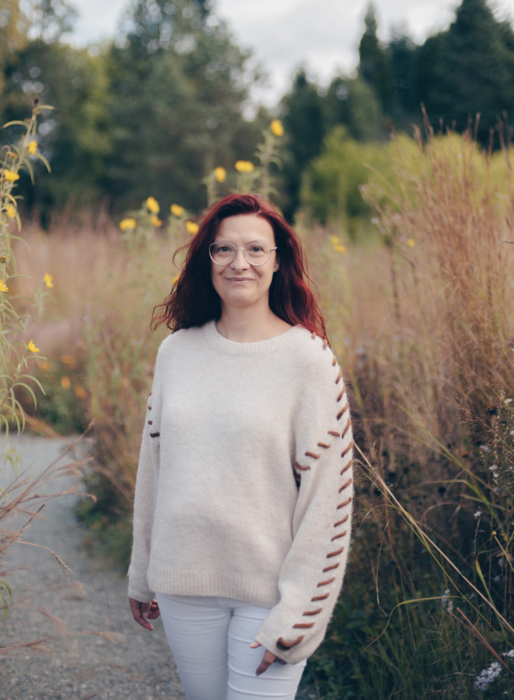 Tanja Wünsch steht inmitten von Blumen und Gräsern und lächelt in die Kamera. Sie hilft Männern mit Prostata Probleme Bayreuth.